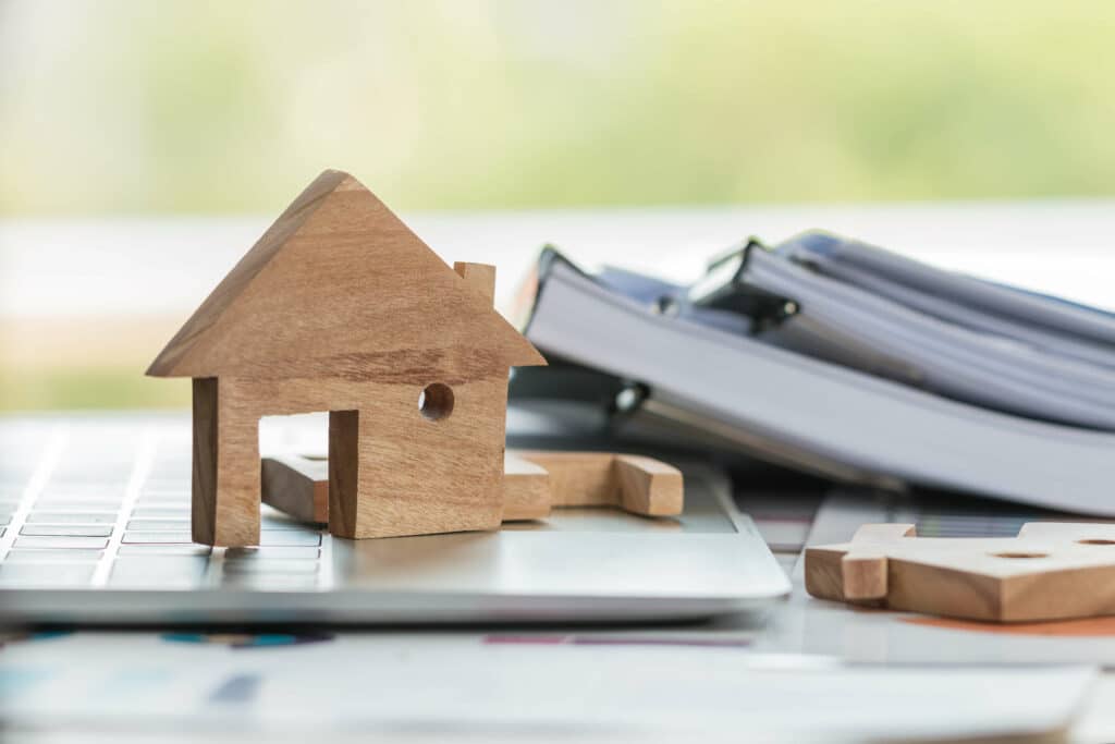 Wooden model house next to house title documents